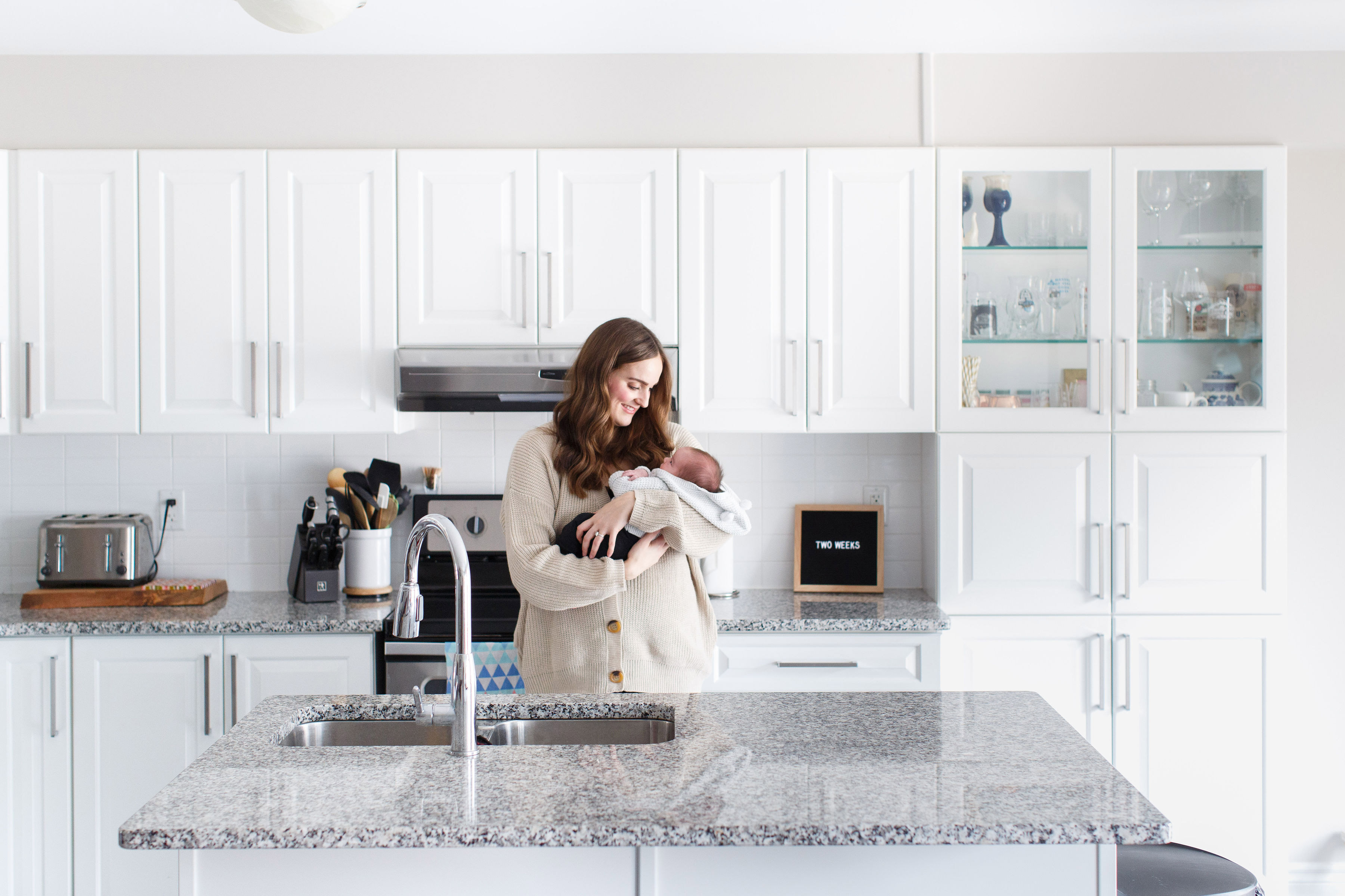 indoors intimate newborn photoshoot showing mom holding baby in kitchen