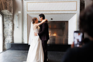 a wedding couple dance in front of a fire