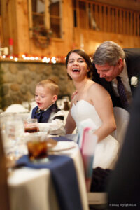 a bride laughs as someone tells her a story at her reception