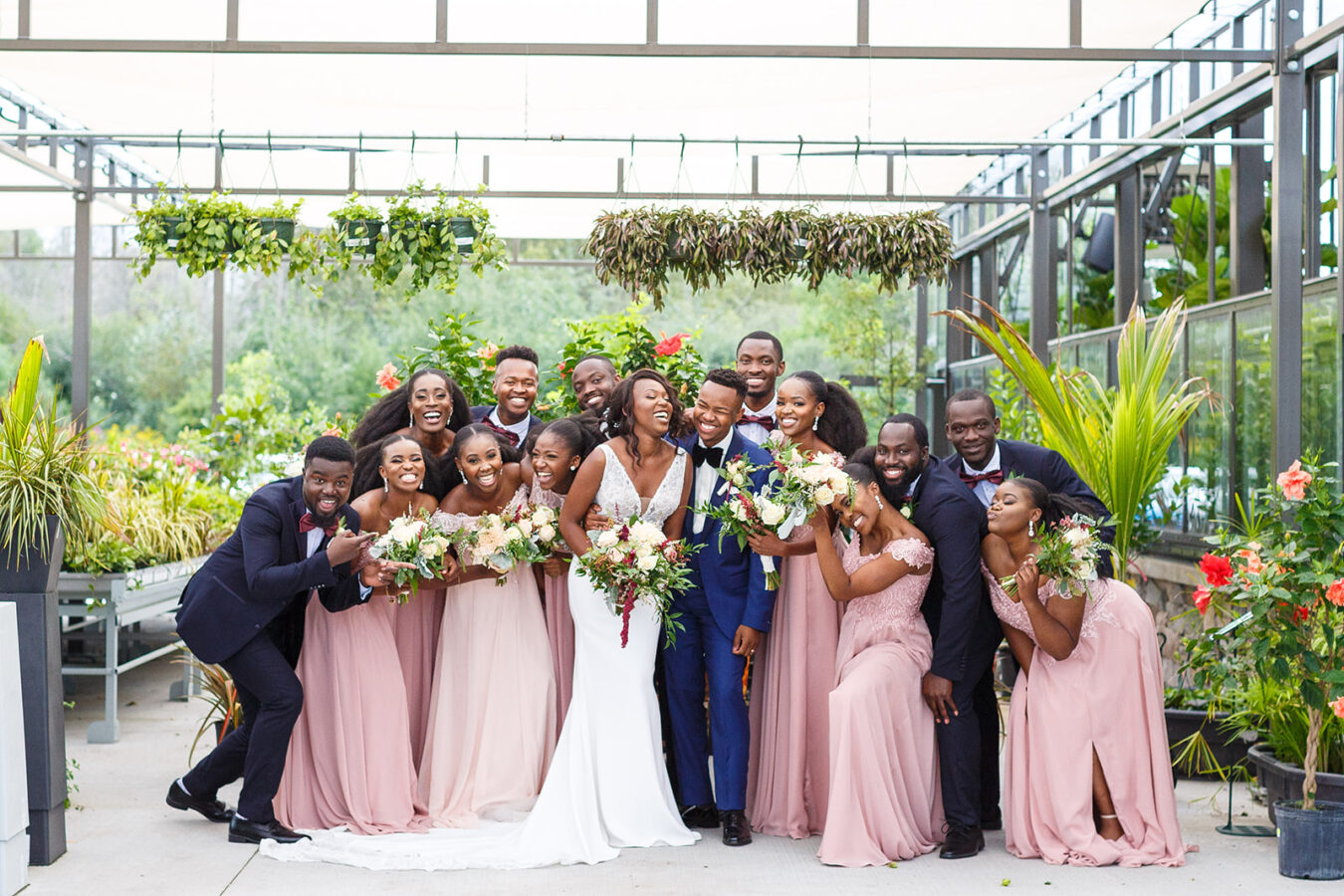 A bridal party laugh in a greenhouse
