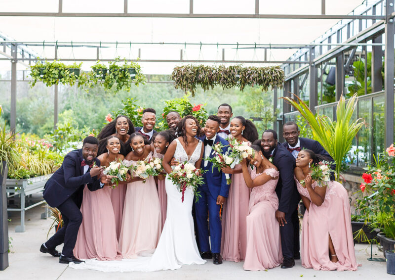 A bridal party laugh in a greenhouse