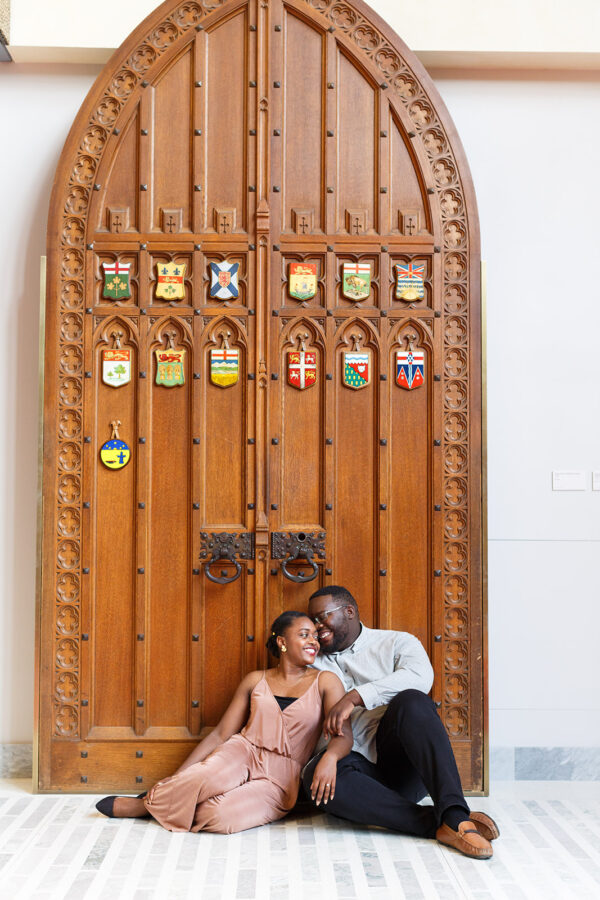 a happy couple sit in front of a big vintage door laughing
