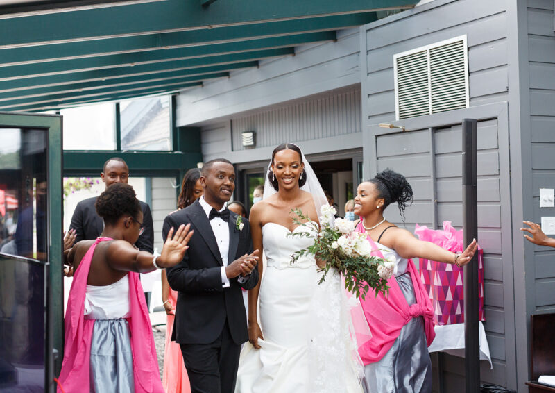 A beaming bride is walking with her new husband and bridesmaids