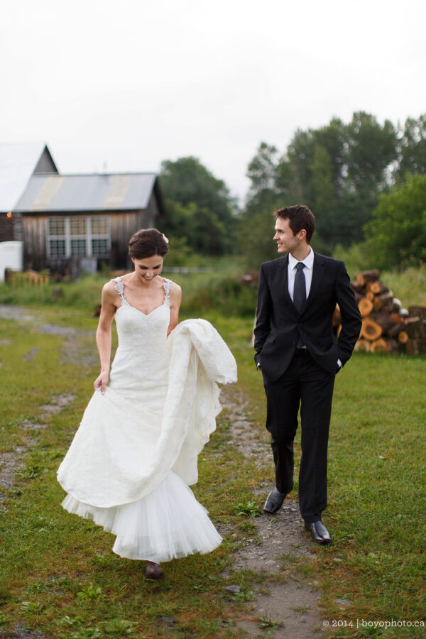 Stylized Rustic Wedding Ottawa, a bride and groom walk in the countryside with a barn in the background.