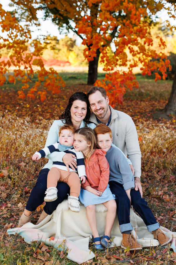 Family of five on blanket in golden reeds wearing blue and grey