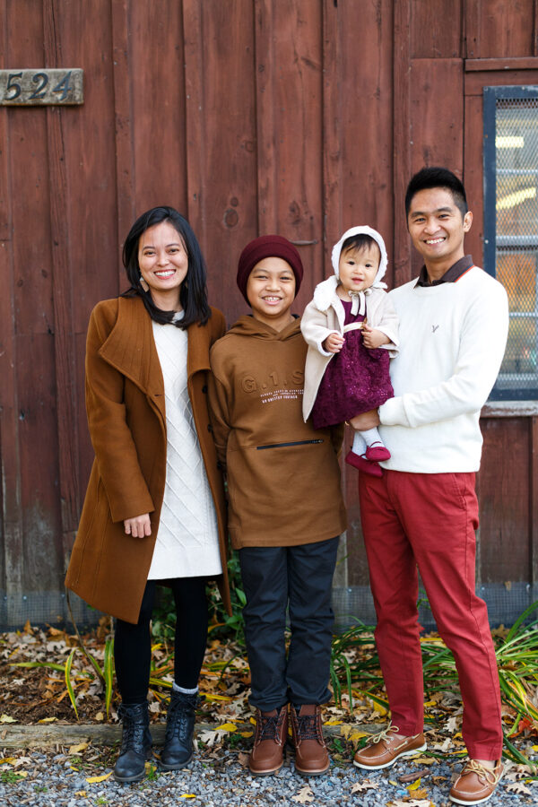Young family of four in front of village store in fall