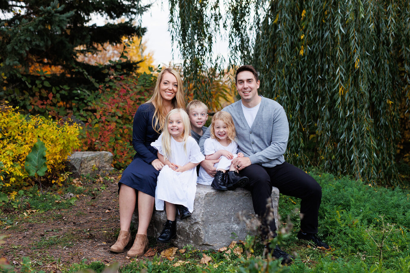 Family of five sitting on rock with fall bushes at Walter Baker