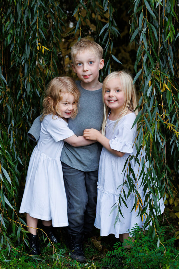 family sitting on bench under fall-coloured tree