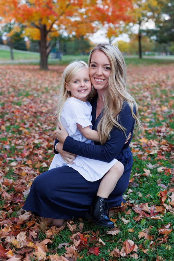 Mother and daughter sitting on fallen leaves