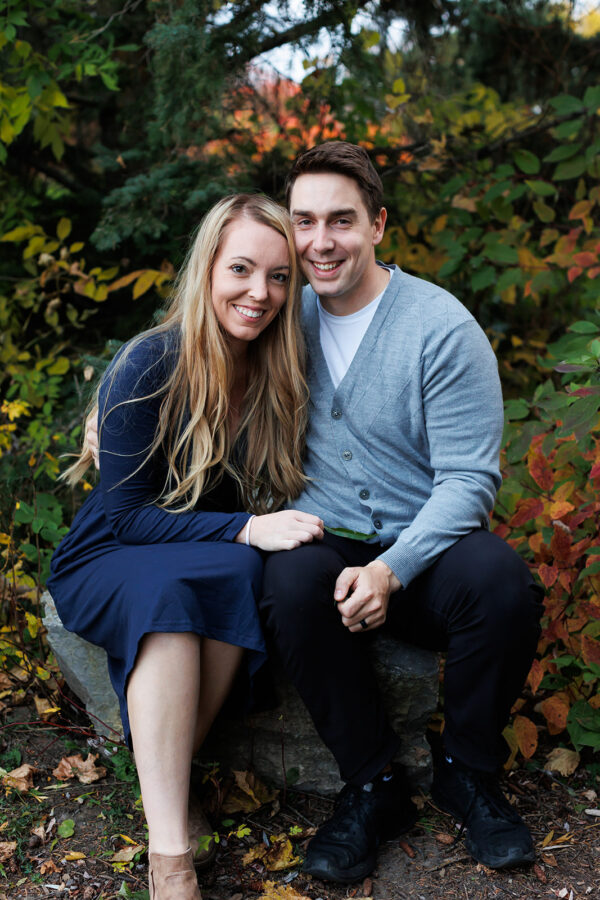 Mom and dad sitting on rock posing for fall portrait
