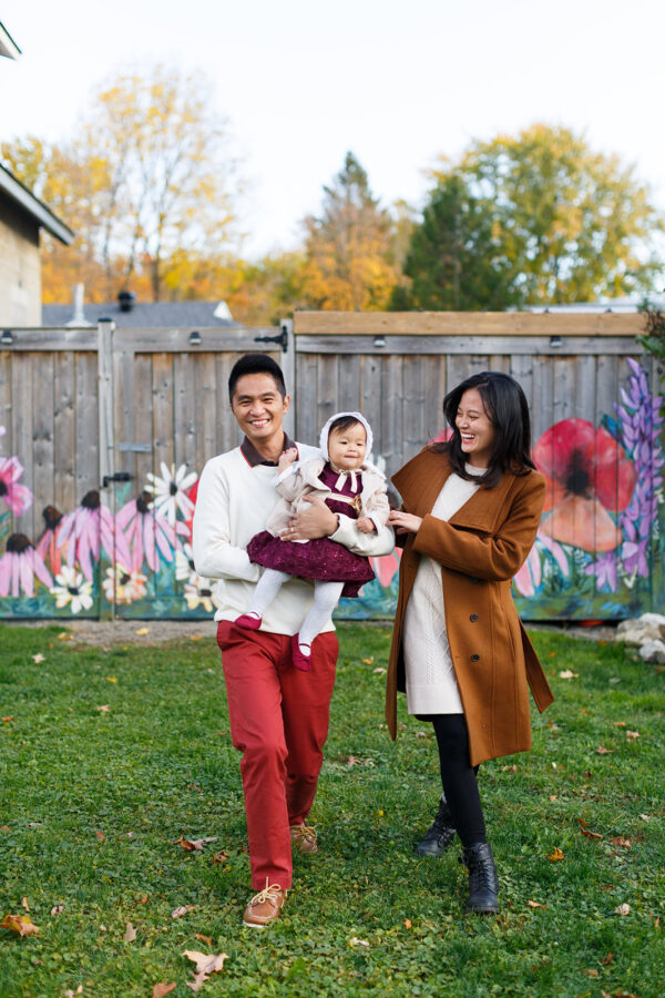 Young family candidly walking on grass carrying a child
