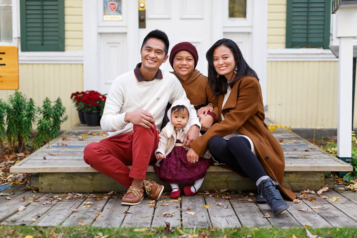 Young family with two kids sitting on heritage home steps